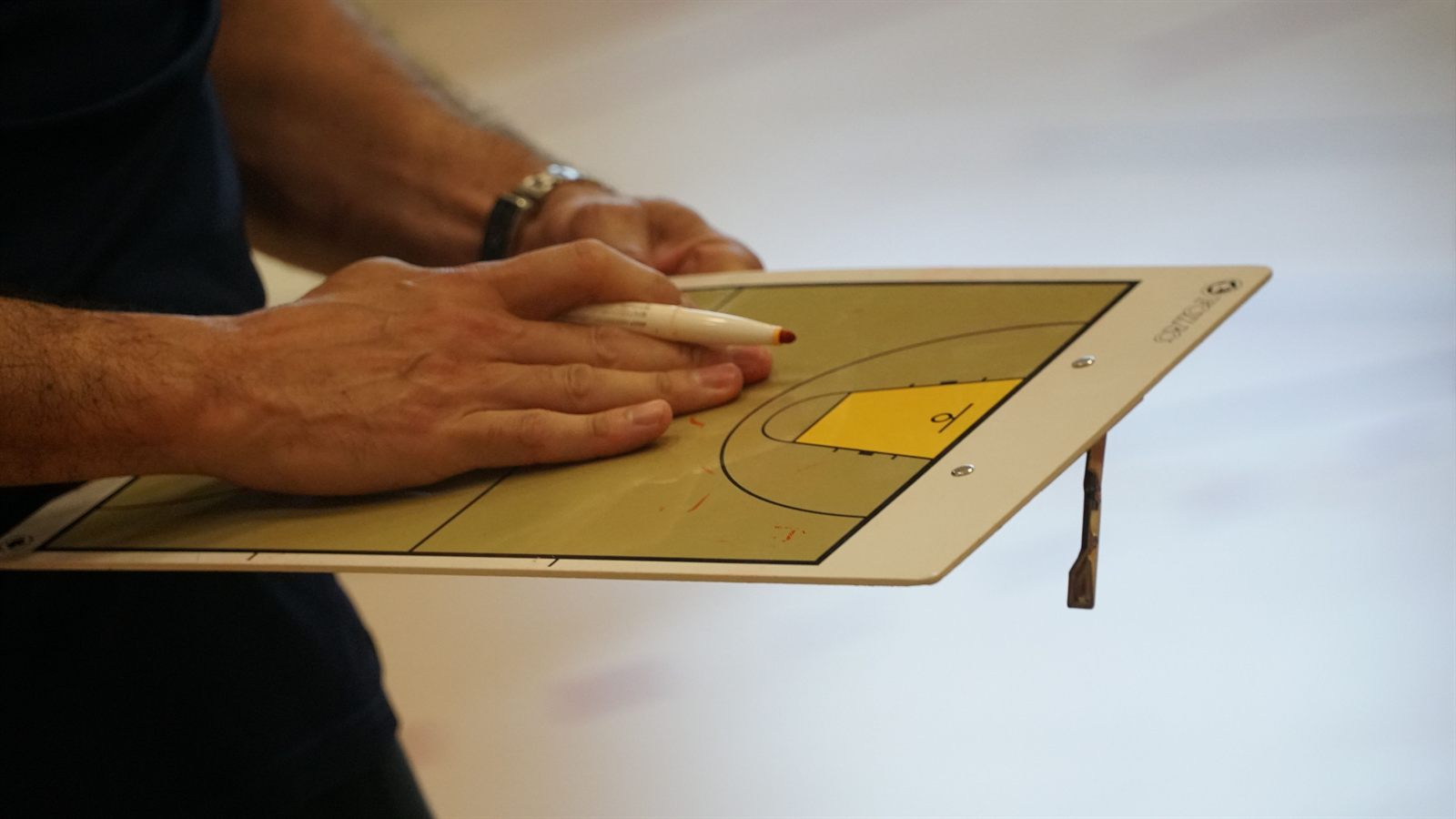 Main d'entraîneur utilisant un tableau tactique pendant une préparation sportive